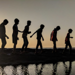 Silhouettes of individuals strolling along the shoreline during a picturesque sunset on the beach