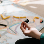 A person engaged in a board game involving a train, strategically maneuvering game pieces on a colorful game board.